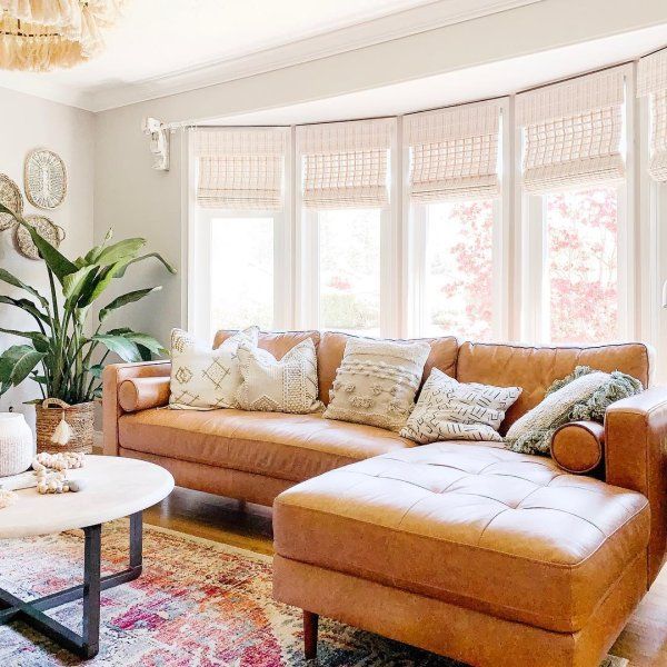 a living room filled with furniture and a large window covered in shades of light brown