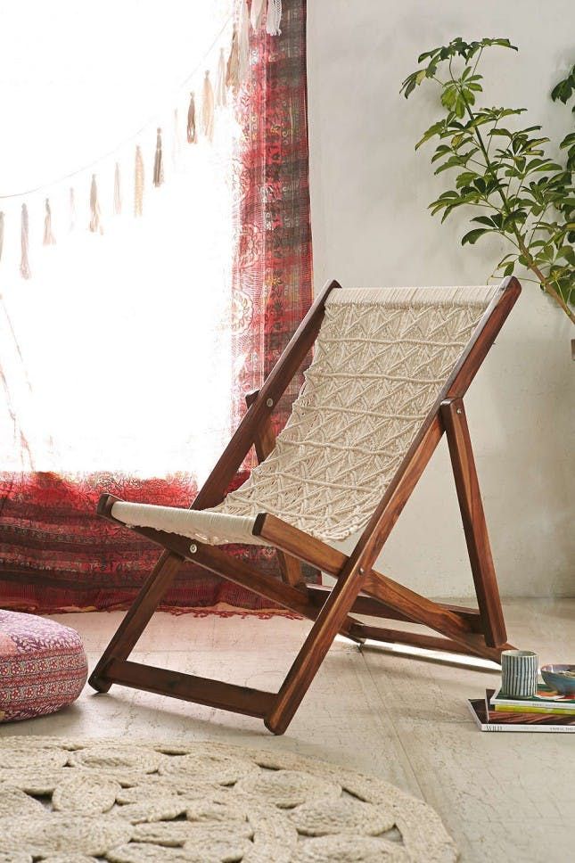 a wooden chair sitting on top of a rug next to a potted plant in front of a window