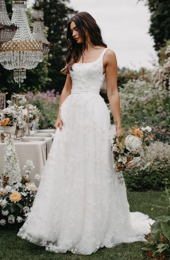 a woman in a wedding dress standing next to a table with flowers and chandeliers