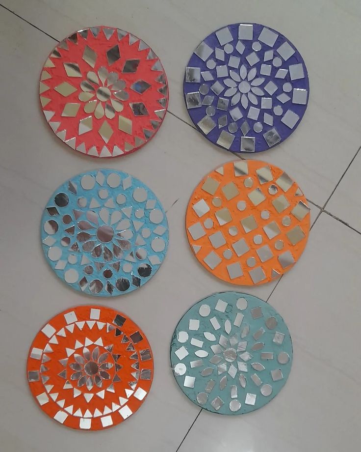 four different colored plates sitting on top of a tile floor next to each other with holes in them