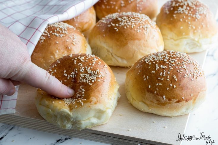 a person placing sesame seed on top of buns