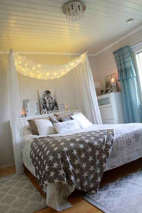 a bedroom with a bed, curtains and lights on the ceiling is decorated in gray and white