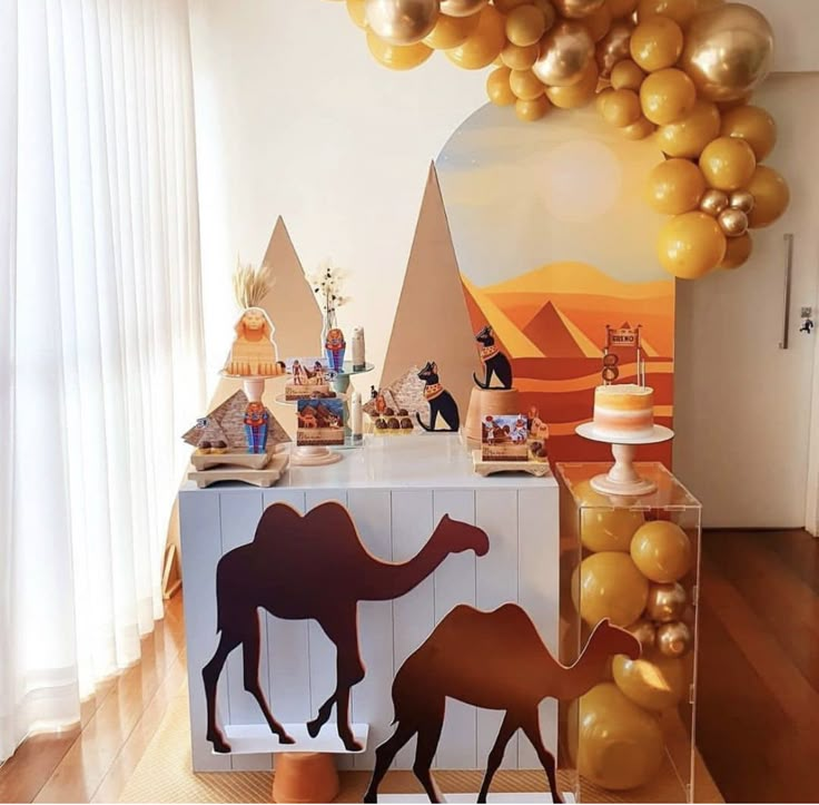 a dessert table with balloons and camels on it