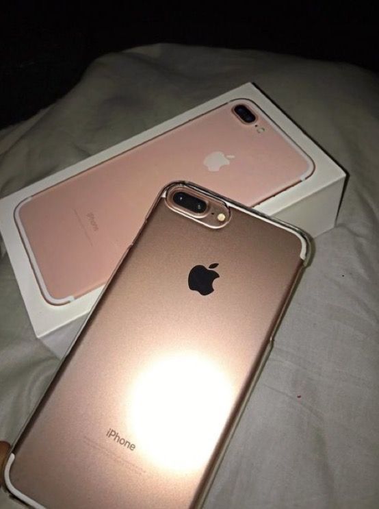 two iphones are sitting next to each other on a bed, one is gold and the other is pink