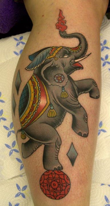 an elephant tattoo on the leg of a woman's leg, which is decorated with red and blue designs