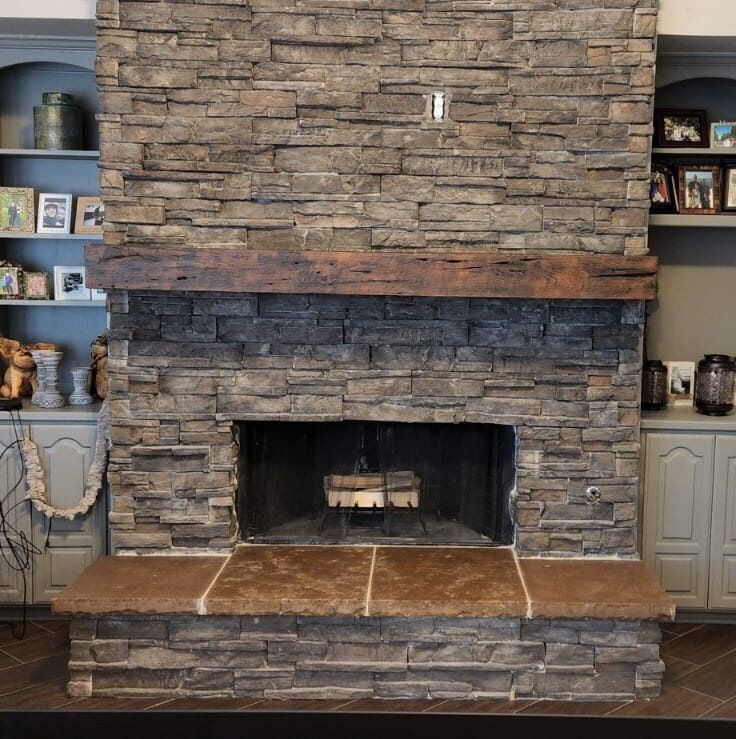 a living room with a stone fireplace and shelves