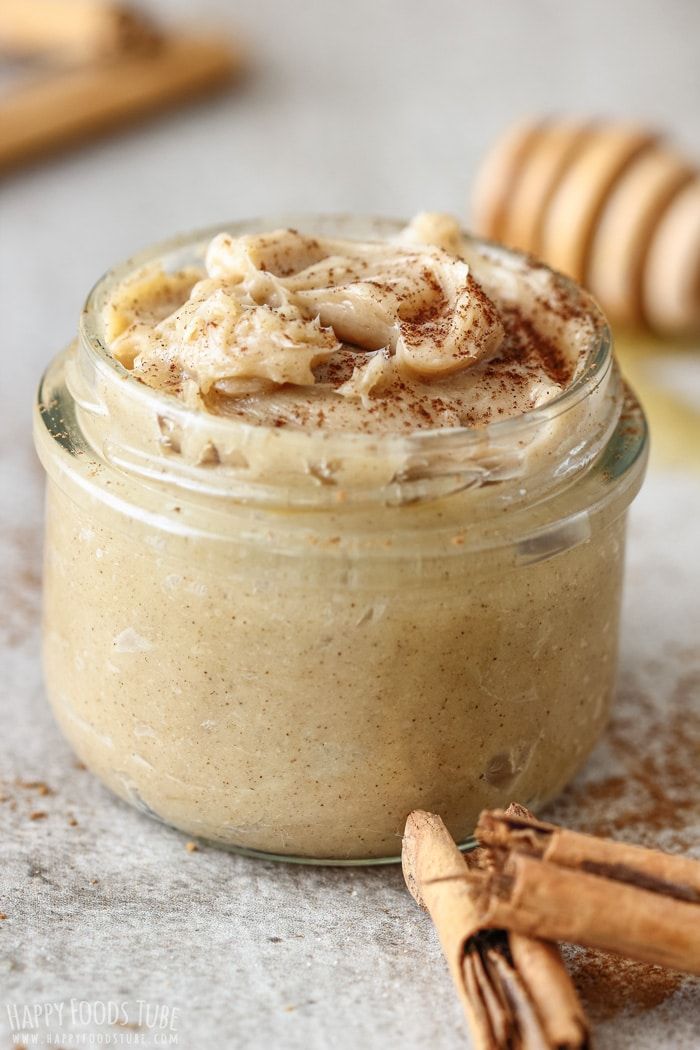 a jar filled with cinnamon butter and topped with whipped cream next to some cinnamon sticks