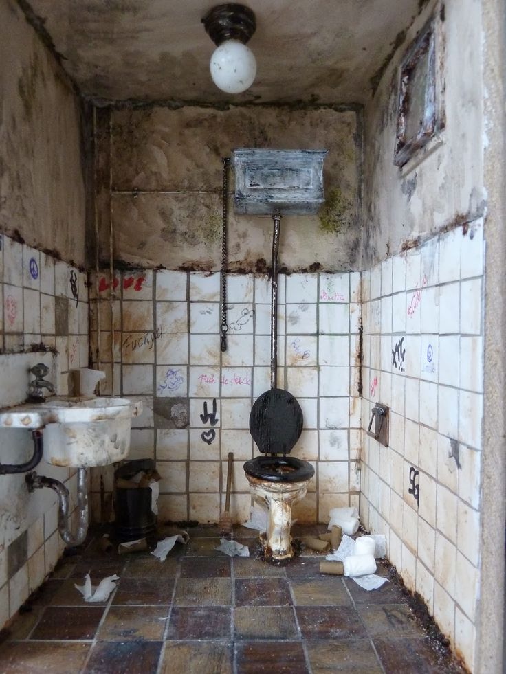 a dirty bathroom with toilet and sink in it