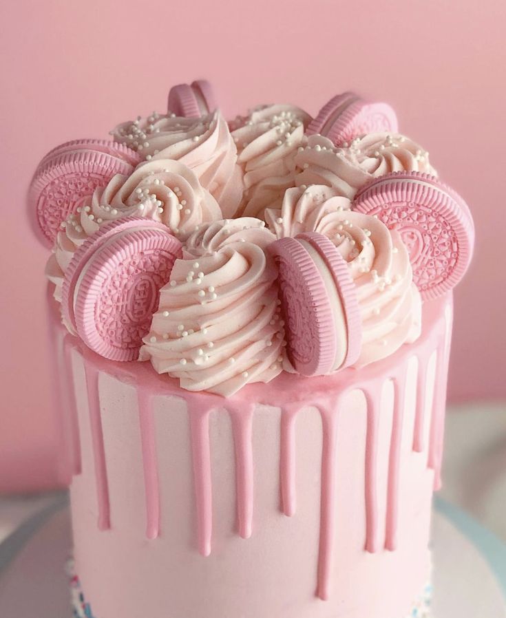 a pink cake with white frosting and cookies on top