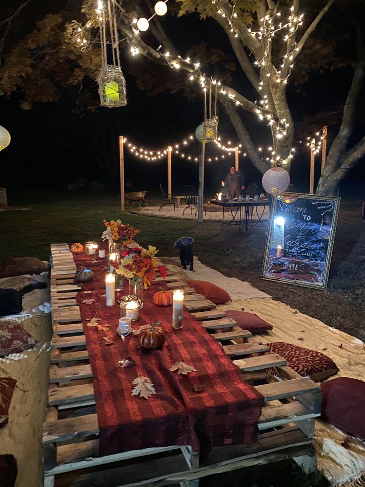 a long table with candles on it in the middle of a yard at night time