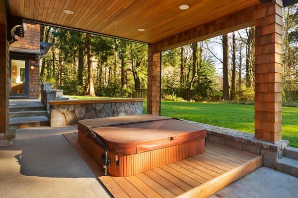 a hot tub sitting on top of a wooden deck next to a lush green field