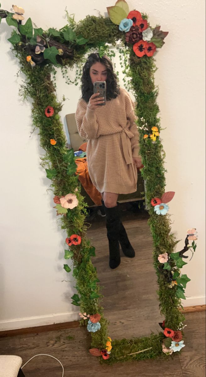 a woman taking a selfie in front of a mirror with flowers and vines on it