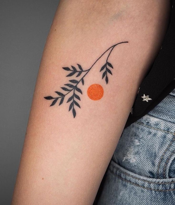 a woman's arm with an orange and black branch tattoo on the left upper arm