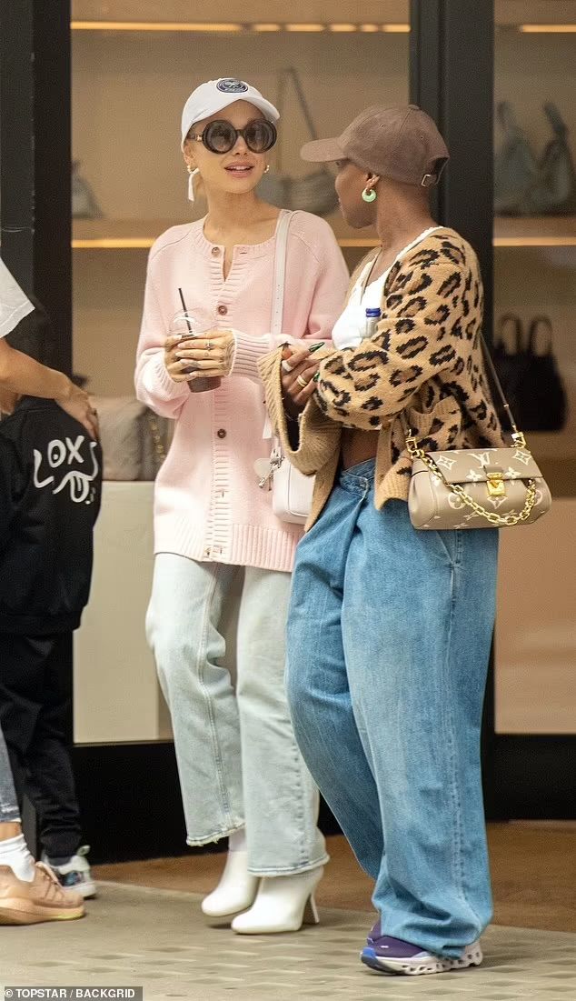 two women are standing on the sidewalk and talking to each other while holding coffee cups