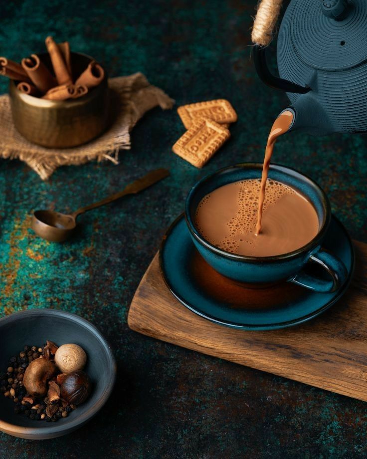 a cup of hot chocolate being poured into a mug with nuts and cinnamons on the side