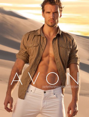 a man with no shirt on standing in the sand wearing white pants and a tan jacket