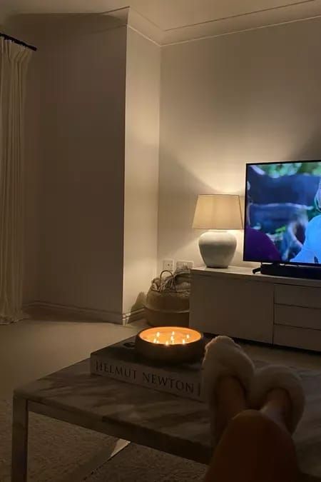 a person is watching television in the living room with their feet propped up on a coffee table