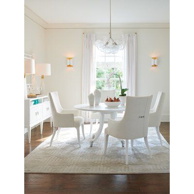 a white dining room table and chairs in front of a window with light coming through