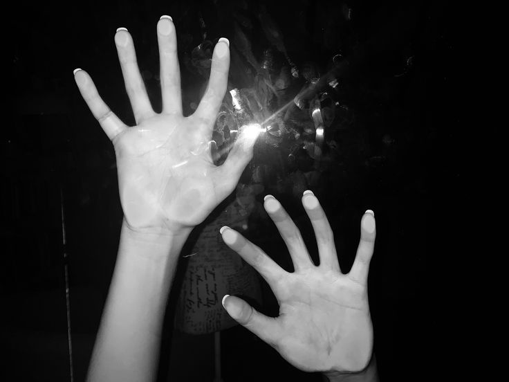 two hands reaching up towards each other in the dark