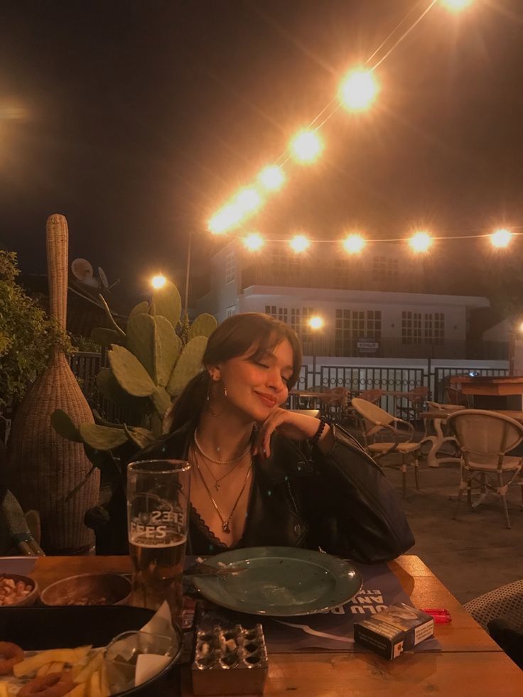 a woman sitting at a table with food and drinks