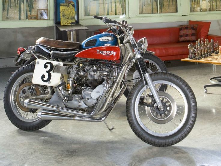 a red and black motorcycle parked in a garage next to a table with chess pieces on it