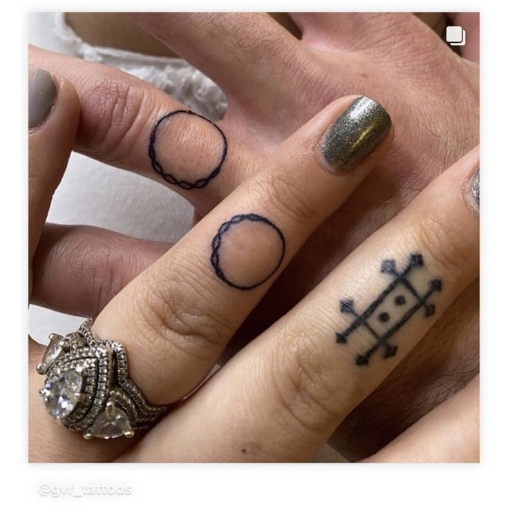 two people with rings and tattoos on their fingers