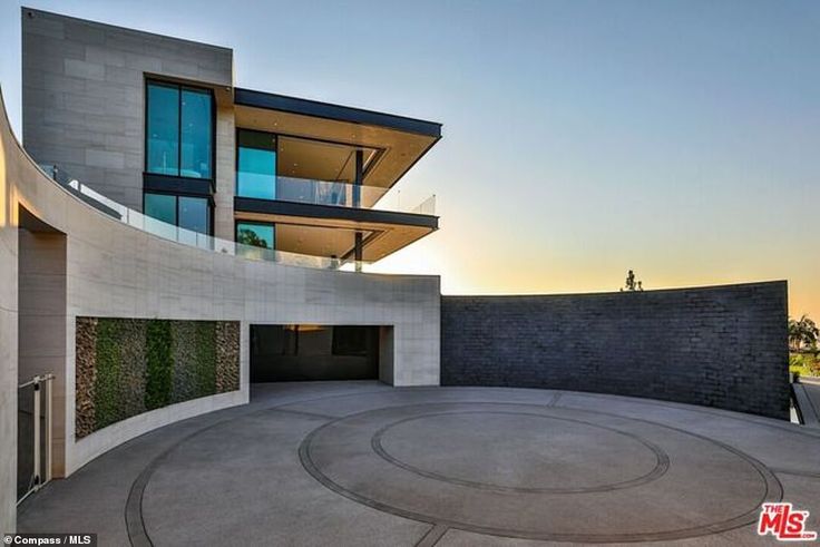 an empty circular concrete area in front of a modern building with glass balconies