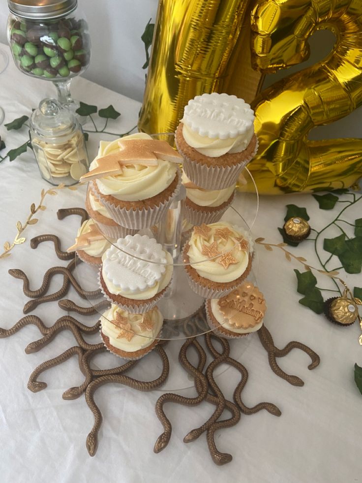 cupcakes are stacked on top of each other with gold foil balloons in the background