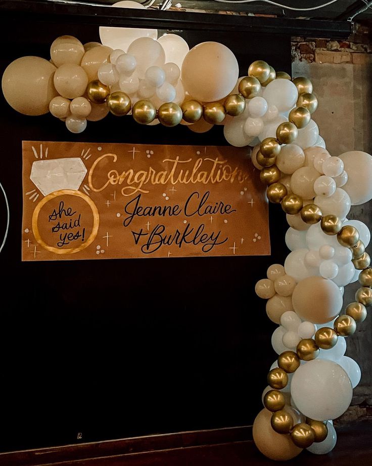 an arch made out of balloons with congratulations written on the front and gold trimmings