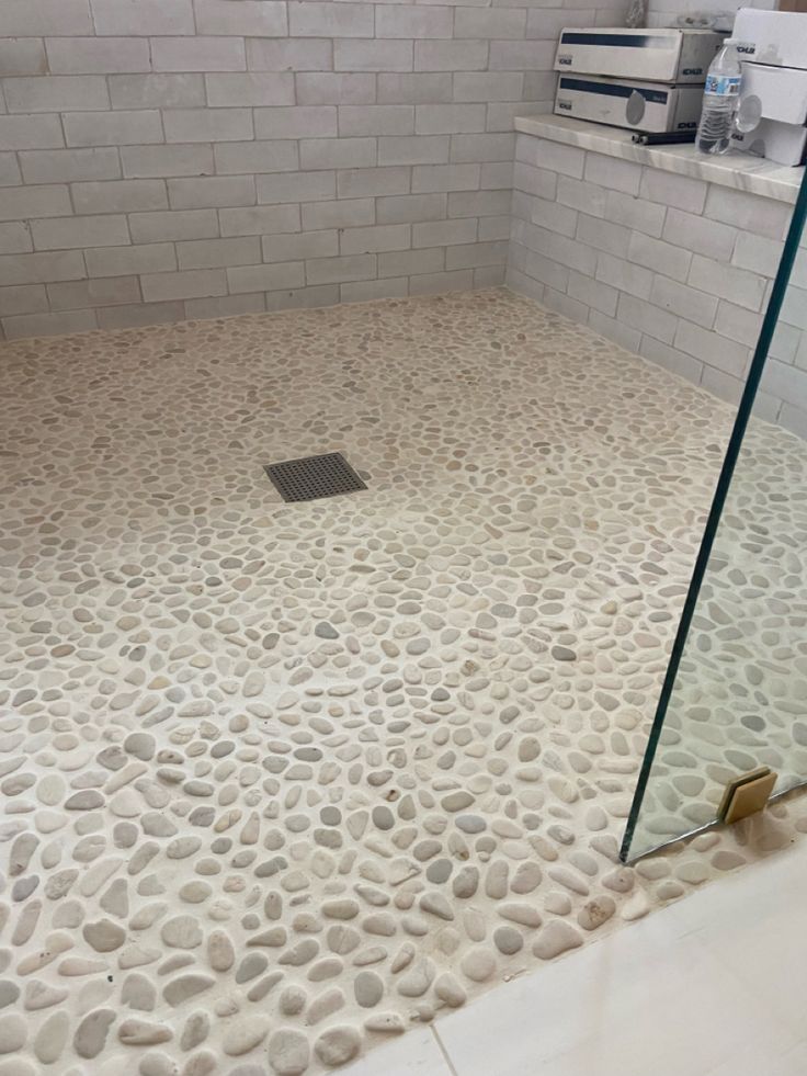 a bathroom with pebbles on the floor and a glass shower door