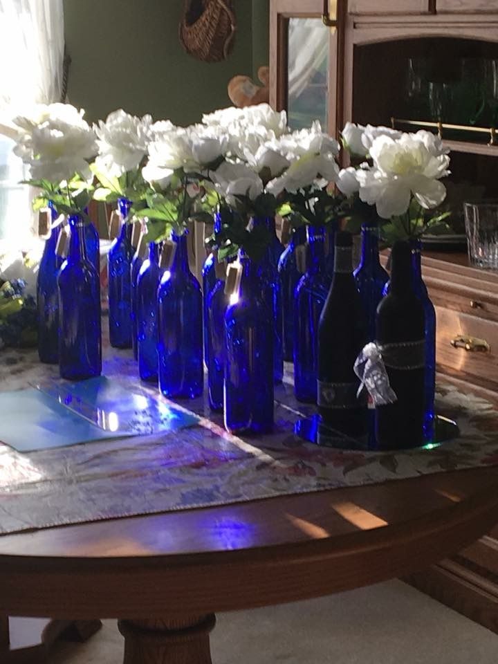 there are many blue bottles with white flowers in them on the table and one is empty