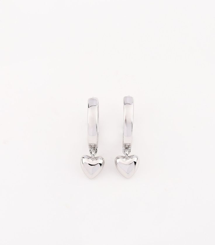 These cute silver hoops are adorned with a dainty heart charm, adding a touch of elegance to your ear stack. At 11mm in diameter, they are the perfect size for layering. Each earring weighs only 2-3 grams, providing a lightweight and beautiful addition to your daily look. In stock and ready to ship. Handmade in India. Pair with the Princess Bangle in Silver and Daisy Studs to complete your silver look! White Gold Huggie Jewelry For Valentine's Day, Valentine's Day White Gold Huggie Jewelry, Sterling Silver Huggie Heart Single Earring, Sterling Silver Huggie Heart Earring, Sterling Silver Single Huggie Heart Earring, Elegant Sterling Silver Huggie Earrings With Heart Charm, Small Hoop Sterling Silver Heart Earrings Hypoallergenic, Elegant Sterling Silver Huggie Earrings With Dangling Charms, Heart-shaped White Gold Hoop Earrings For Valentine's Day