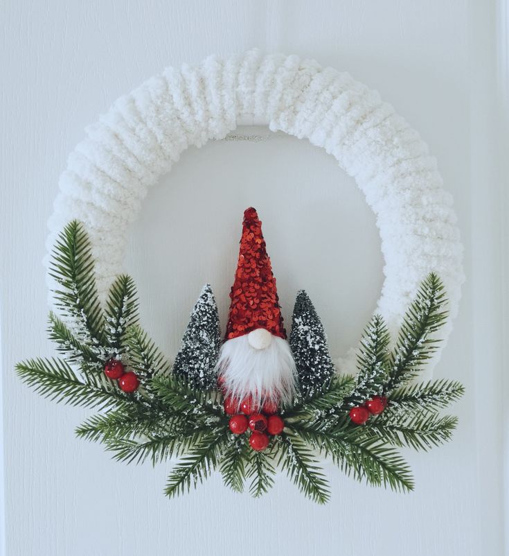 a christmas wreath decorated with pine cones, holly and santa's helper hat