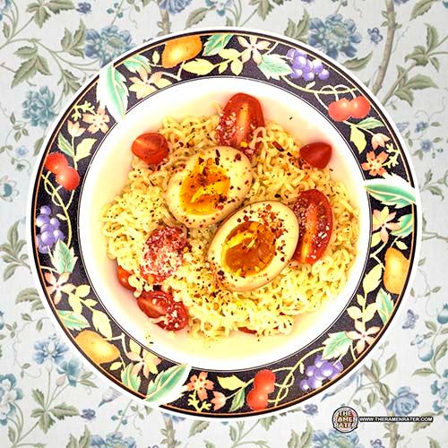 a bowl filled with rice and eggs on top of a floral table cloth next to a spoon