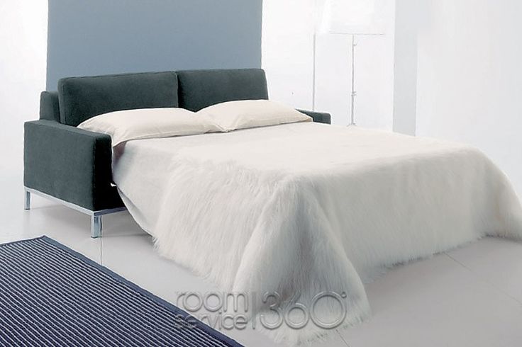 a bed with white sheets and pillows in a room next to a blue rug on the floor