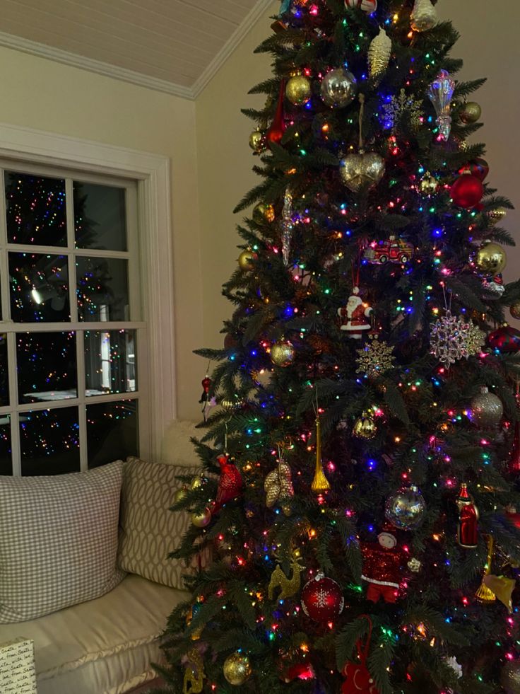 a decorated christmas tree in front of a window