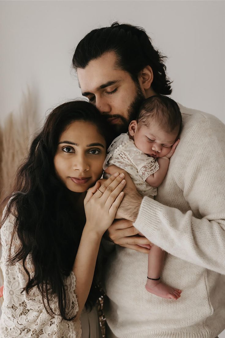 a man and woman holding a baby in their arms