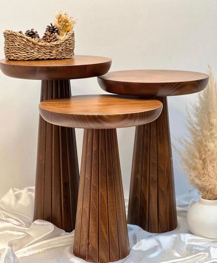 two wooden tables sitting next to each other on a white cloth covered table with a basket