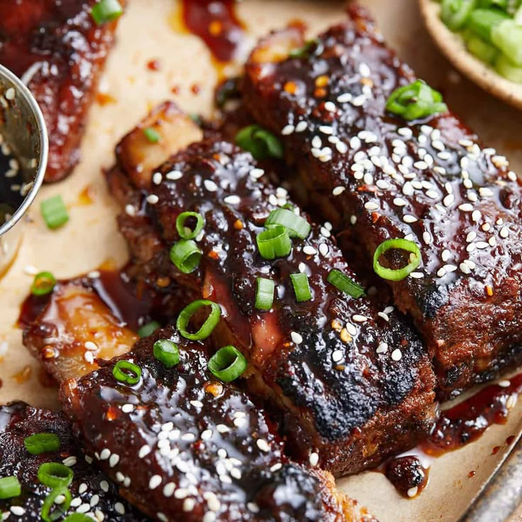 ribs covered in sesame seeds and garnished with green onions on a platter