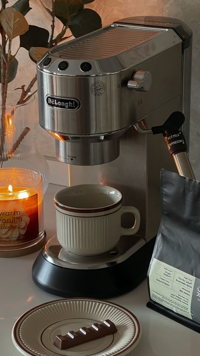 a coffee maker sitting on top of a counter next to a cup and saucer