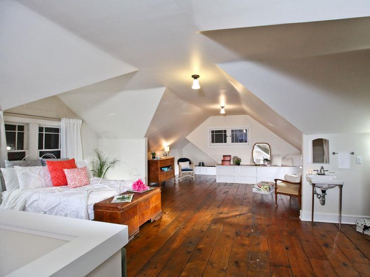 an attic bedroom with wood floors and white walls