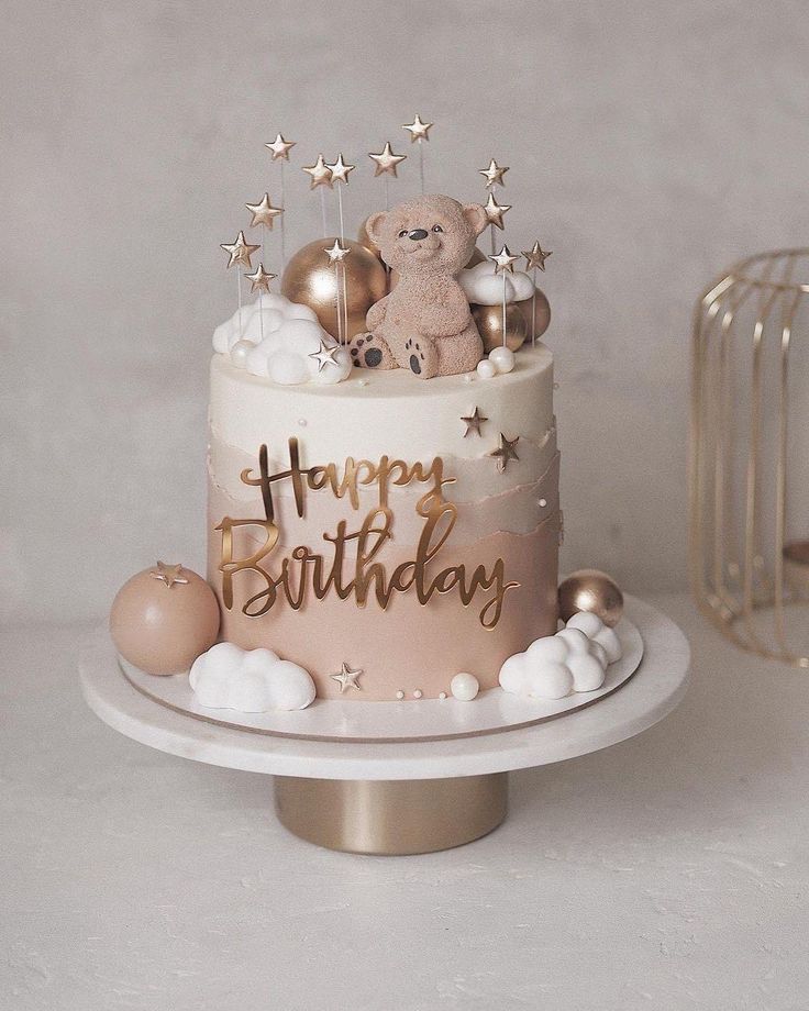 a birthday cake decorated with gold stars and a teddy bear