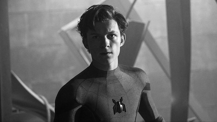 black and white photograph of a man in a spiderman suit looking at the camera