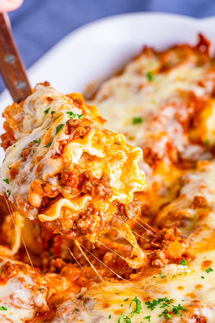 a close up of a person holding a spatula full of lasagna casserole