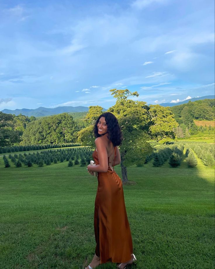 a woman standing on top of a lush green field holding an apple in her hand