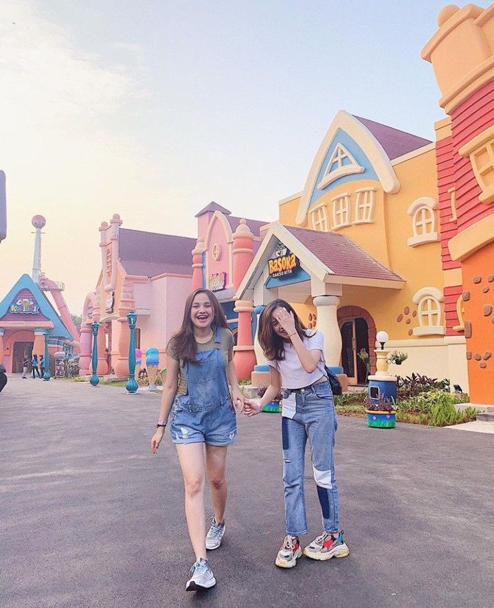 two girls are walking down the street in front of some buildings with colorful houses on them