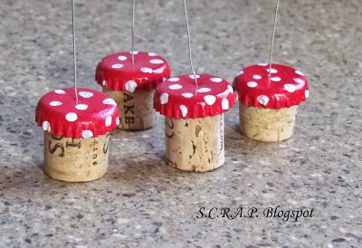 four little red mushrooms sitting on top of a table next to each other with pins sticking out of them