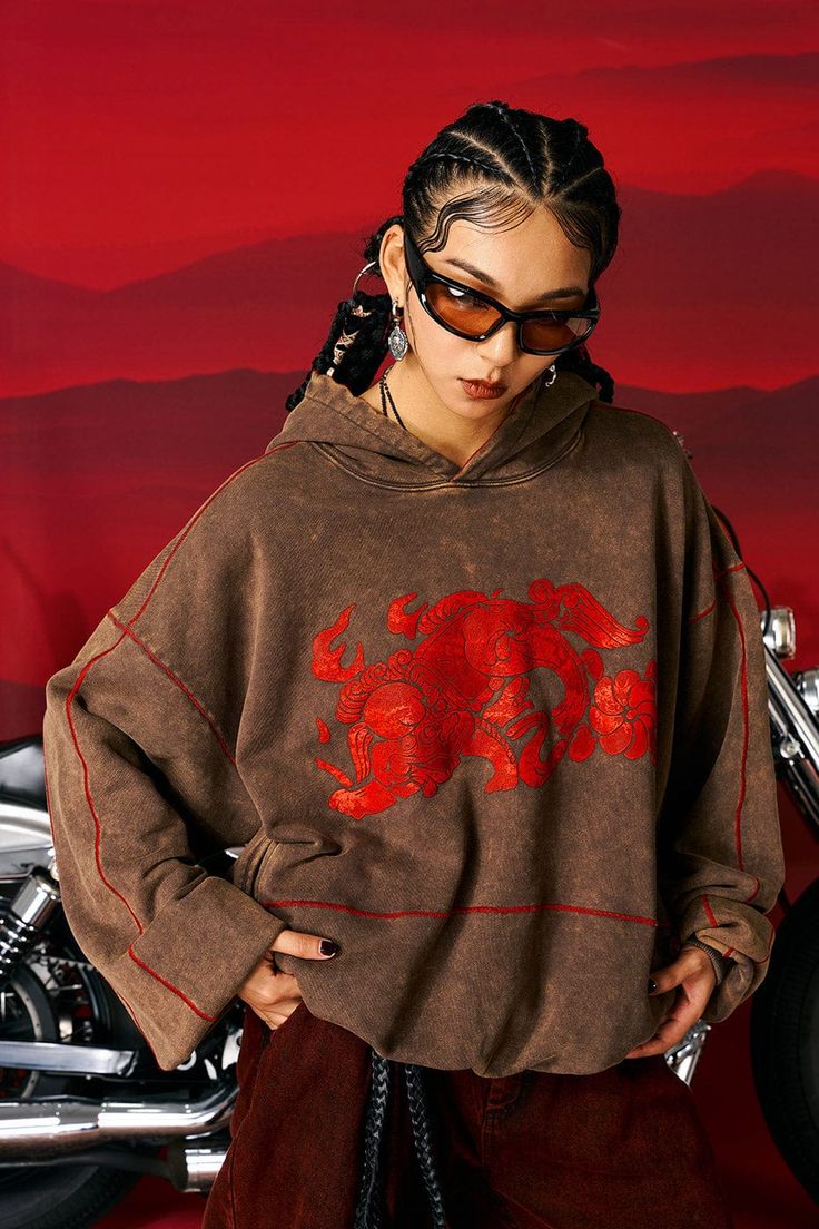 The Lion Heavyweight Oversized Hoodie seamlessly blends traditional elements with bold modern aesthetics, making it a unique addition to your casual wear collection. The hoodie showcases striking lion totem graphics sprawling across the front, accompanied by vibrant red stitches at the seams that instantly catch the eye. The garment underwent a washing process that enhanced its earth-tone color, yielding a rich, layered visual effect. Traditional Chinese knot button closures on the side pockets Earth Tone Hoodie, Unique Hoodies Design, Hoodie Design Ideas Aesthetic, Creative Hoodies, Lion Totem, Camp Hoodie, Hoodie Design Ideas, Graphic Hoodies Aesthetic, Knot Button