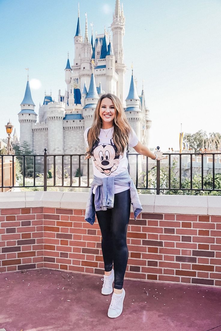 a woman standing in front of a castle with her arms out and smiling at the camera