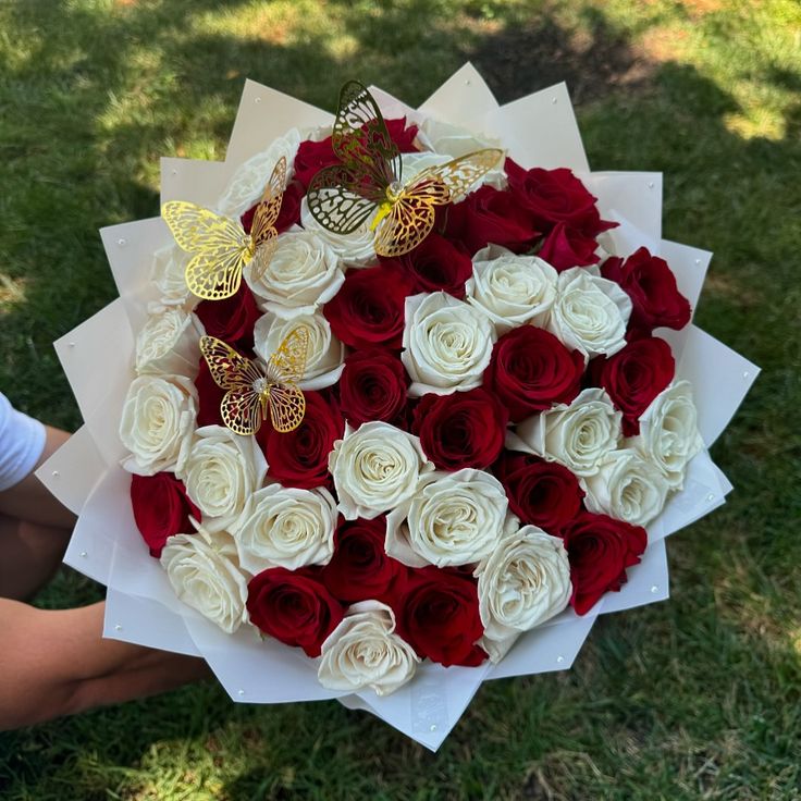 a bouquet of red and white roses in someone's hand